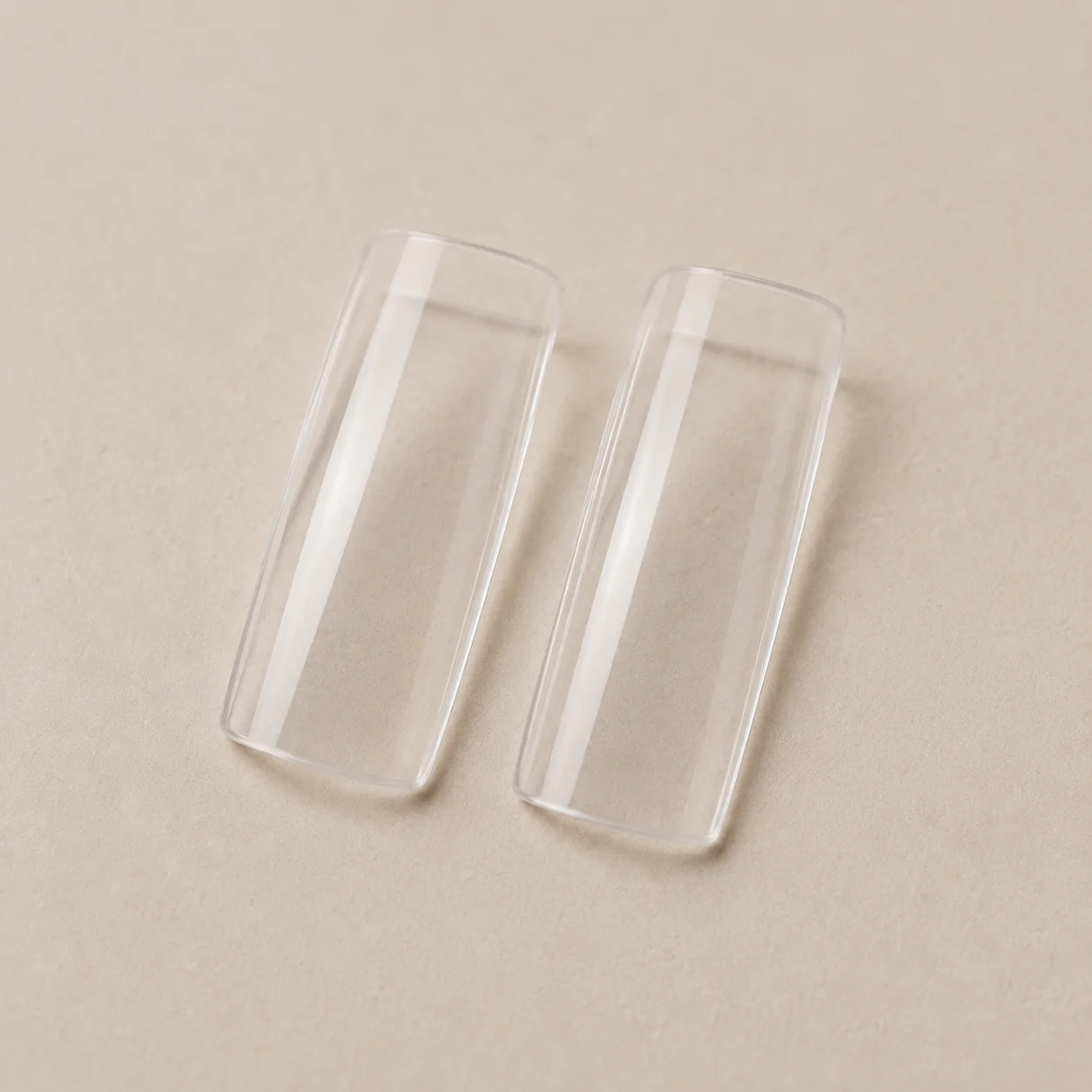 Clear square salon nail tips on beige background